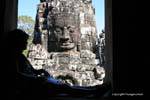 Reading in the shade in front of the stone face, Bayon, Angkor Thom, Cambodia.