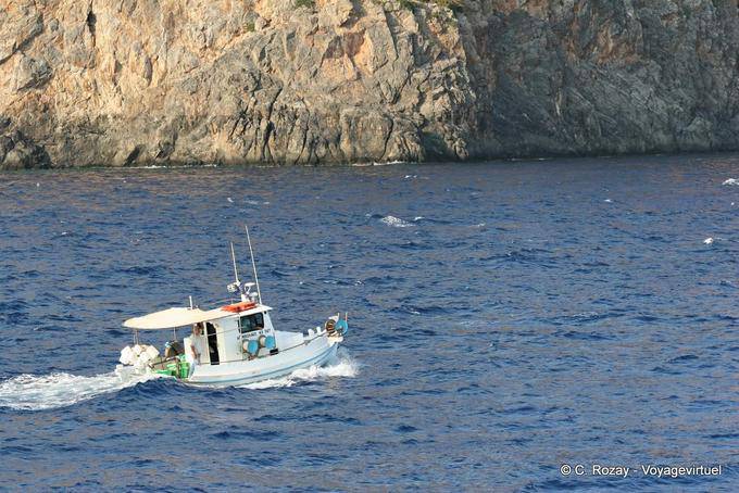 Fishing boat sailing along a cliff Hora Sfakion - Crete, Greece