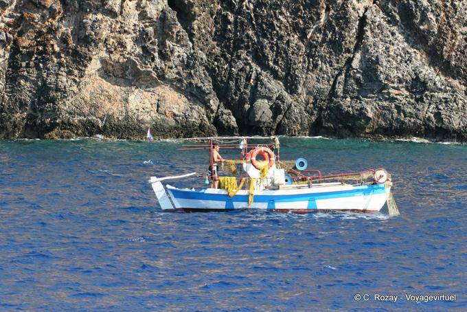 Fisherman in his boat on the edge of the cliffs to Sougia - Crete, Greece