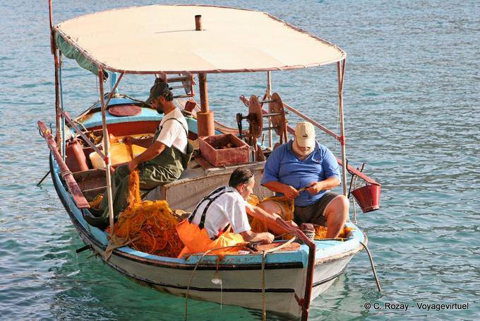 Matala, Fishermen work on their frail craft - Crete, Greece