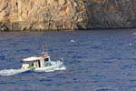 Fishing boat sailing along a cliff Hora Sfakion, Crete.