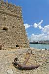 Rusty anchor in front of a wall of the Castello del Molo (Koules), Iraklio (Heraklion), Crete.