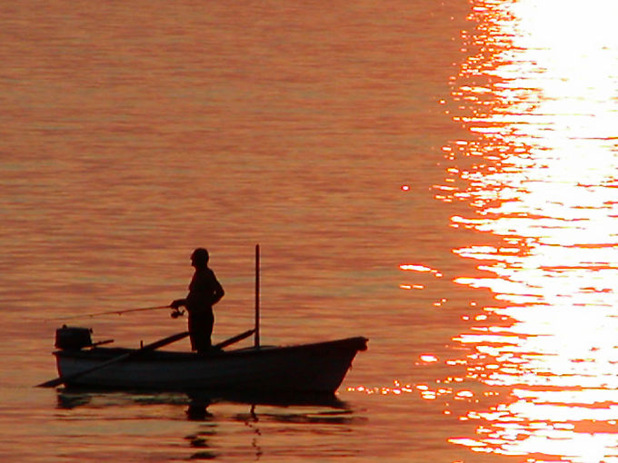 Angler in his boat on the sea reddened by the sun, Starigrad, Croatia
