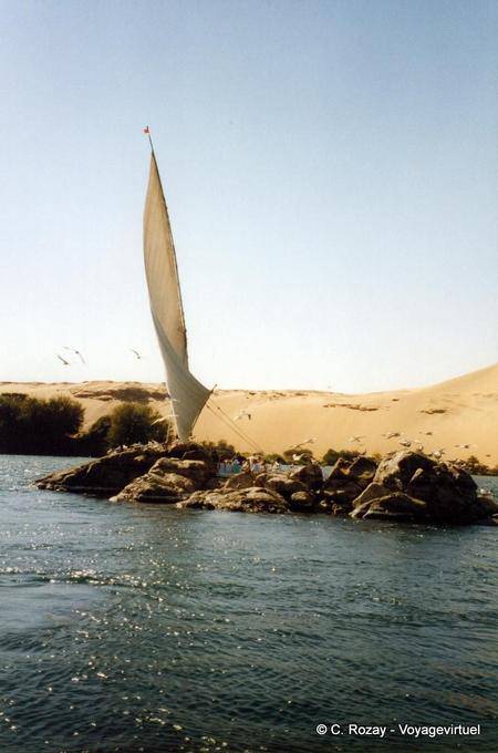 Felucca sailing hidden by an island on the Nile, Aswan - Egypt