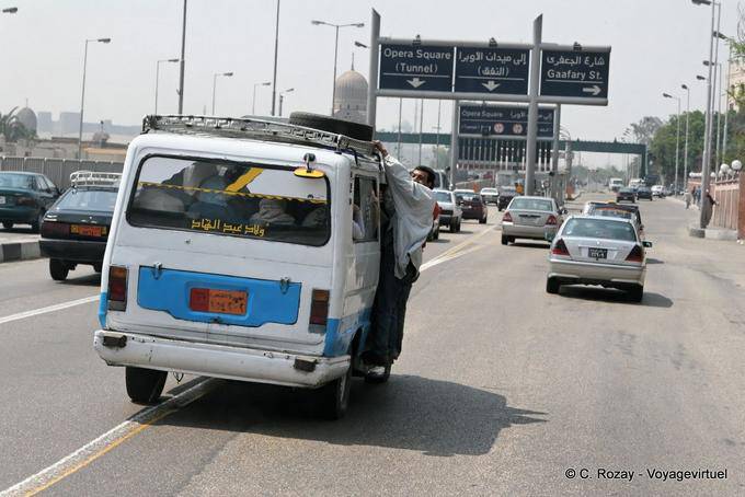 Man hung outside the overloaded taxi, Cairo - Egypt