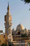 The minaret of the mosque before the domes of the Church of St. George, Aswan, Egypt.