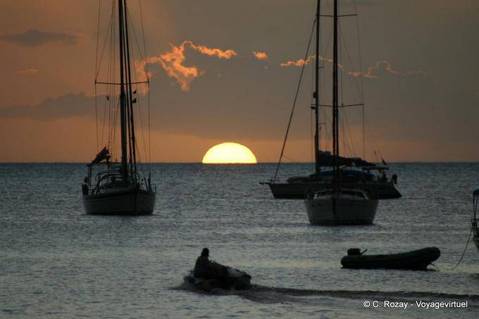 Deshaies, half sun setting between boats in silhouette - Guadeloupe