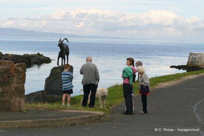 Goat statue (goat), mutton and passers in Cushendun - Nothern Ireland