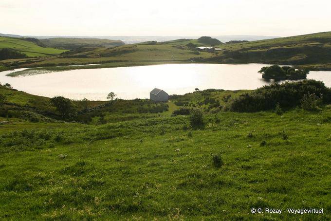 Lough na Cranagh filled with sunshine at the forefront of Fair Head - Nothern Ireland