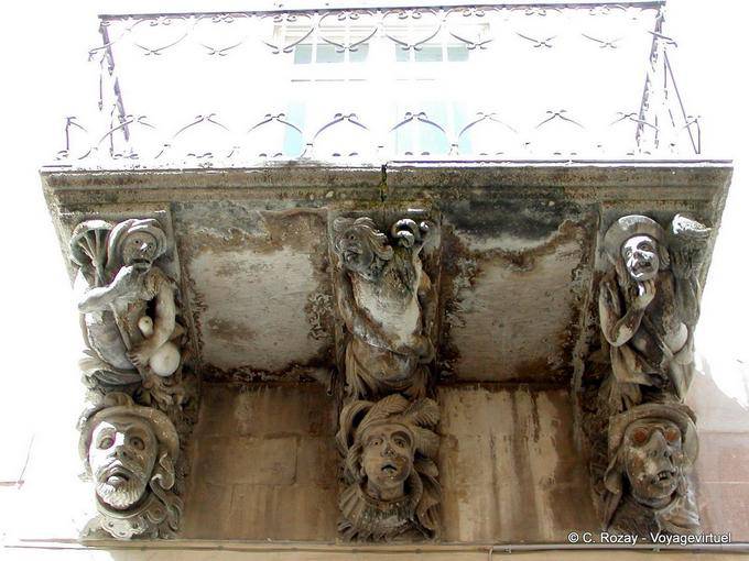 Faces under the balcony, Ragusa, Sicily - Italy