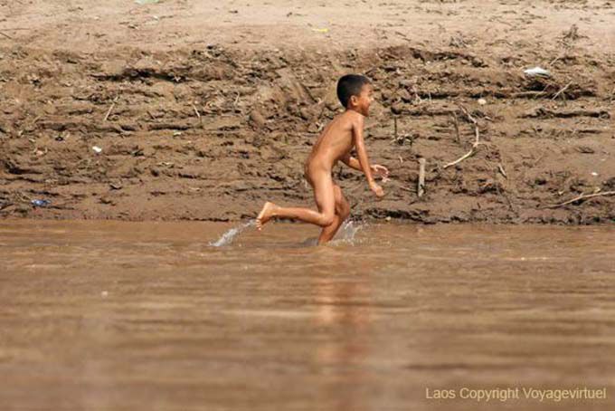 Young Lao running naked on the bank of Mekong Laos Sud, Lao