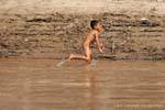 Young Lao running naked on the bank of Mekong Laos Sud, Lao.