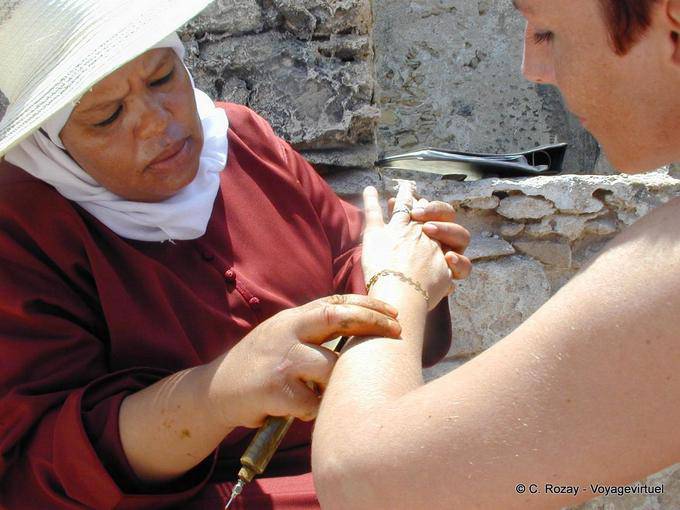 A henna tattoo artist officiating near the ramparts, Essaouira - Morocco