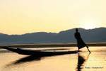 The Intha fisherman sculling with an oar around which winds its leg, Inle Lake, Burma.