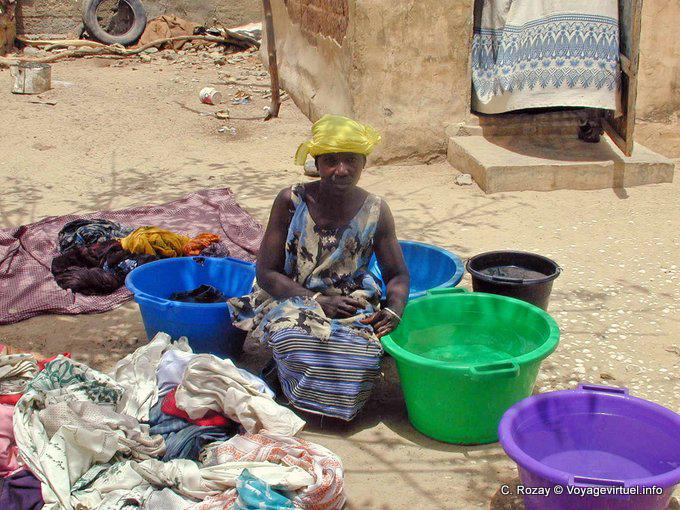 Woman squatting in the middle of multicolored laundry buckets - Senegal