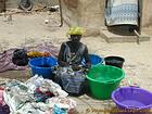 Woman squatting in the middle of multicolored laundry buckets, Senegal.