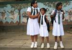 Trio of schoolgirls in uniform in front of a mural, Kandy, Sri Lanka Ceylon.