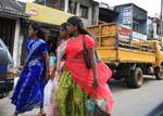 Three young women in saris back racing, street Matale, Sri Lanka Ceylon.